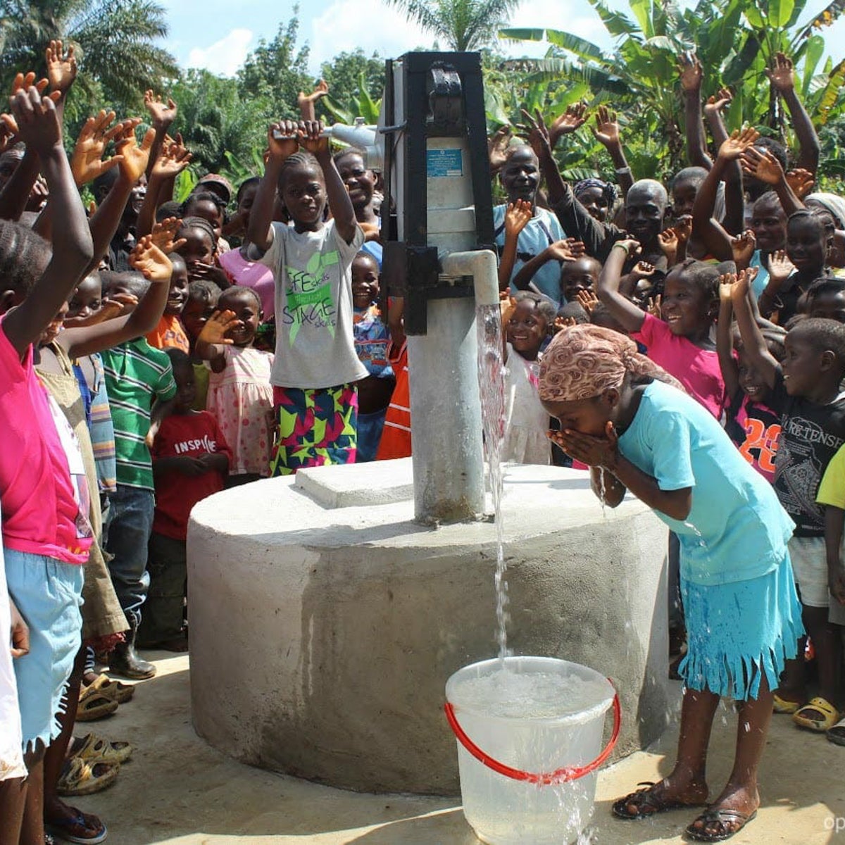 A young Liberian girl drinks deep from one of the new wells OBI built in her area.