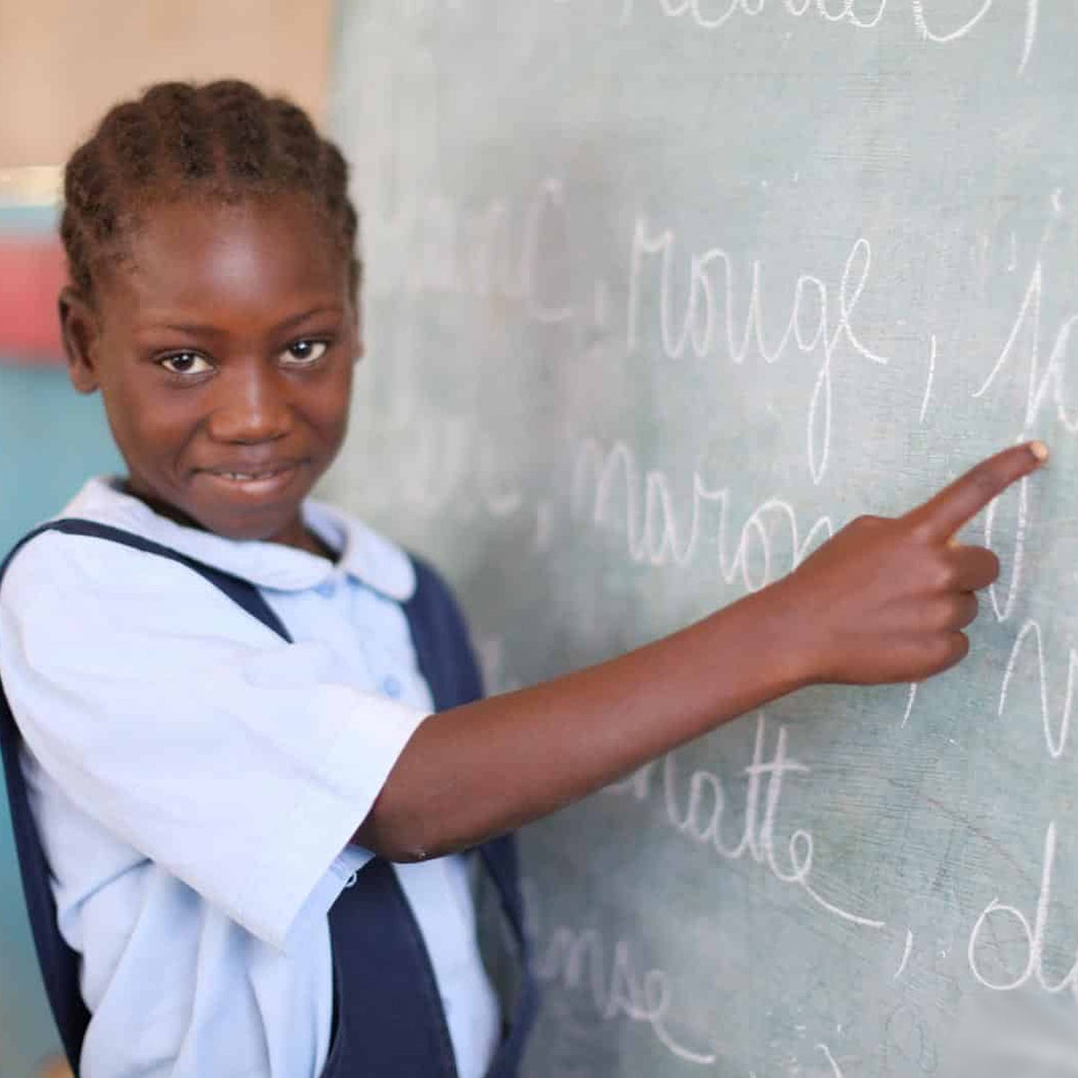 Daphkaline points at the chalkboard. This promising student received a scholarship to continue her education.