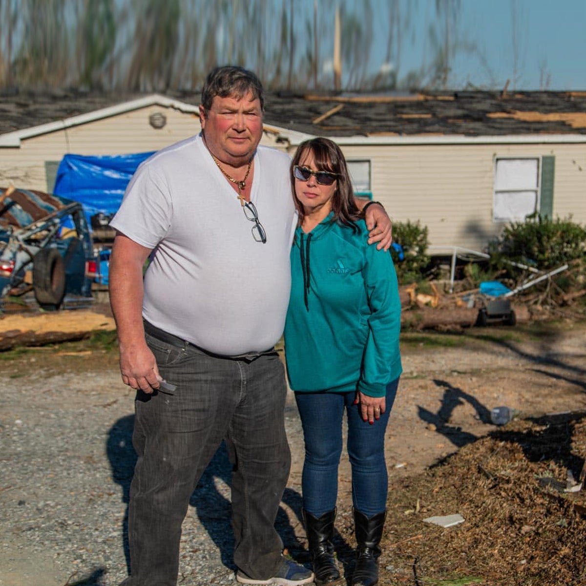 Victims of the Alabama tornadoes stand in front of their damaged home in need of disaster relief.