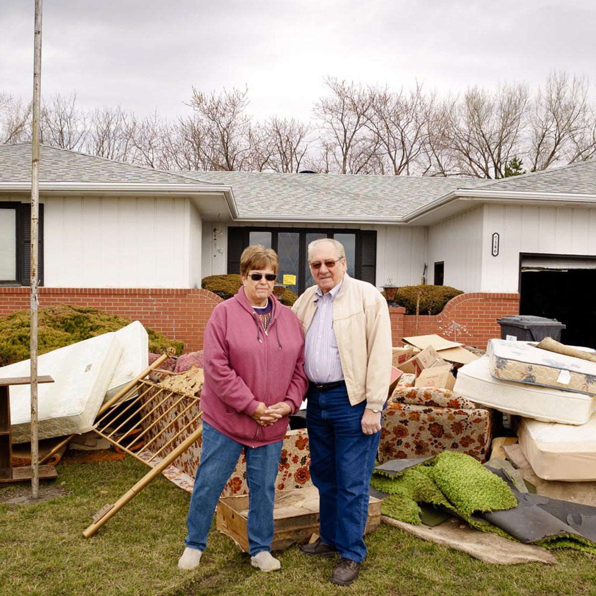 After floods in Nebraska, Linda and her husband, Ralph, stand in front of a pile of flood-soaked belongings.