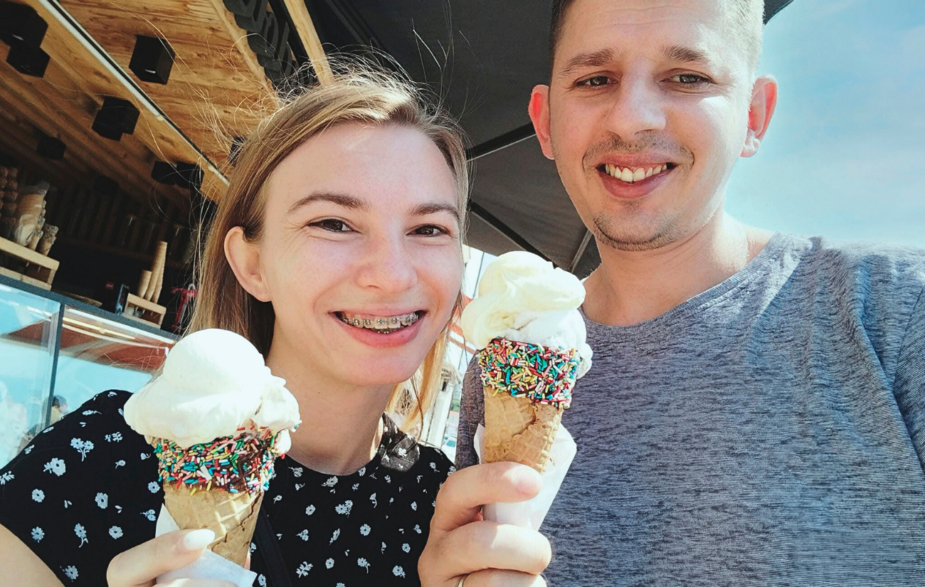 Smiling woman and man holding ice cream cones outdoors.