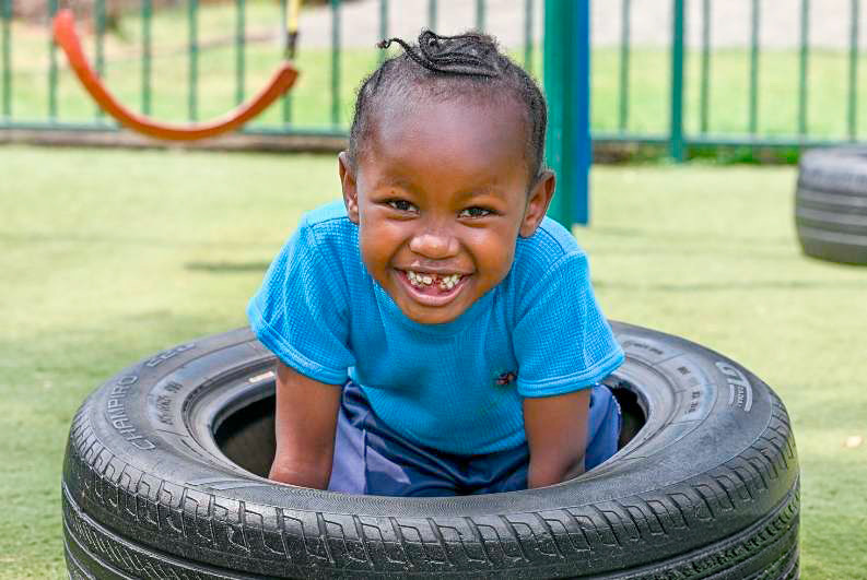 Smiling young child playing inside a tire.
